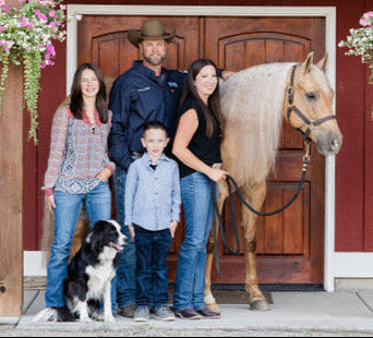Family with a horse in front of a red barn