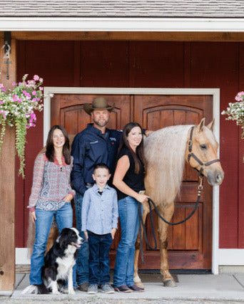 Family with a horse in front of a red barn